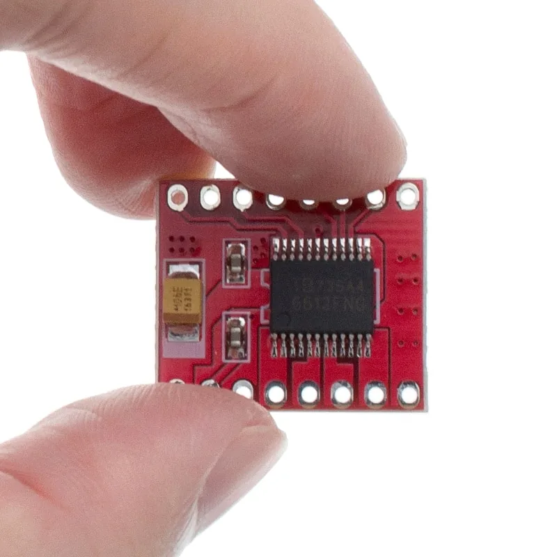 Driver de motores TB6612FNG rojo, sostenido entre dos dedos